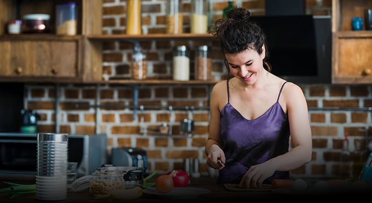 Woman in a kitchen preparing food with a brick wall background